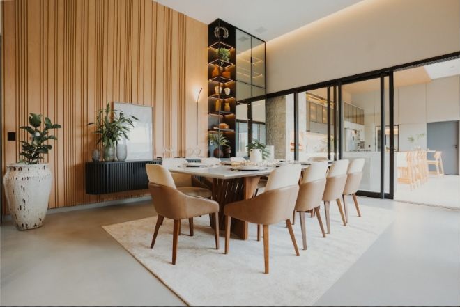 Sala de jantar integrada da Casa Aldeia com mesa central e marcenaria ao fundo