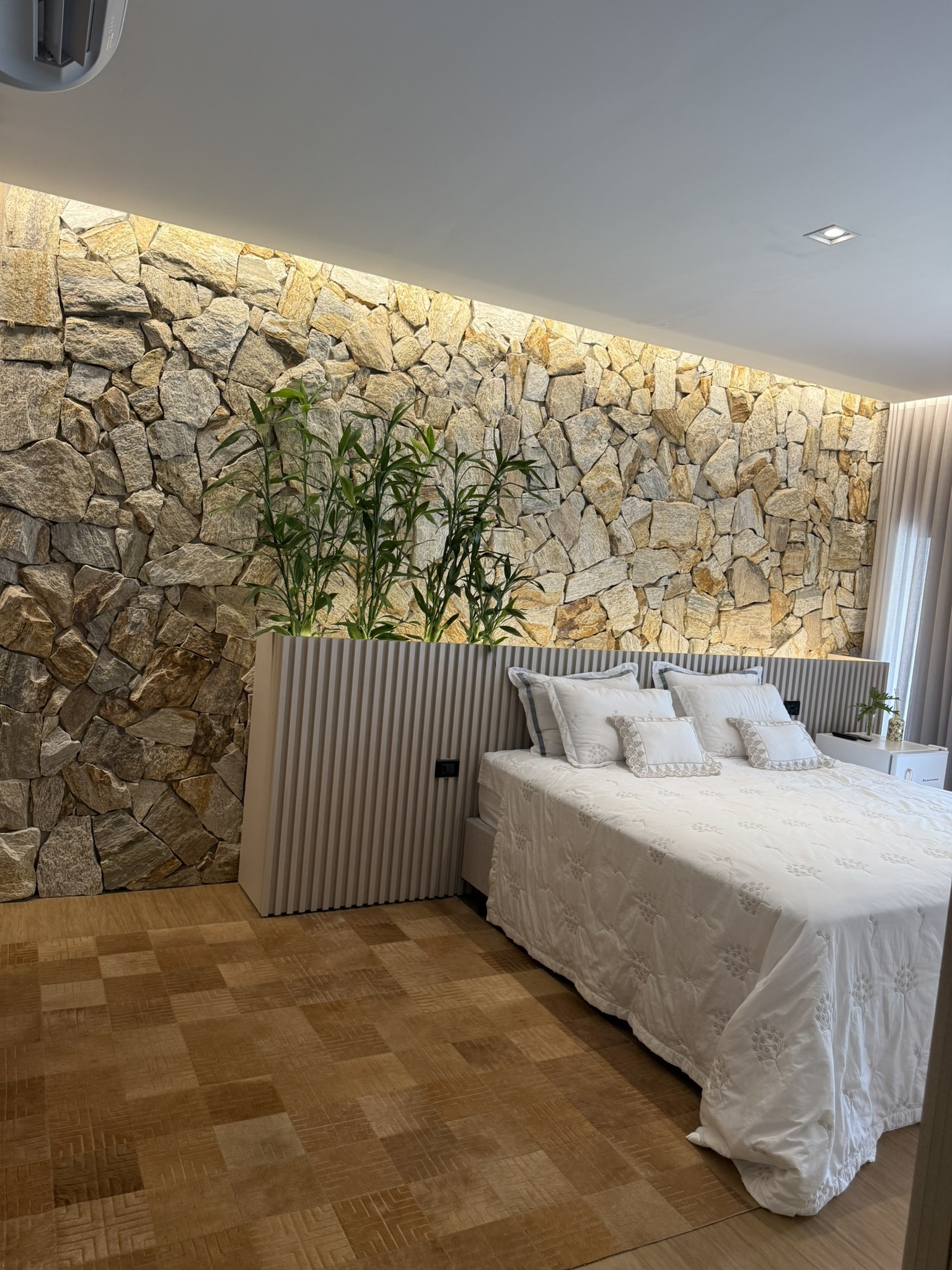 Quarto com parede de pedra e cabeceira ripada