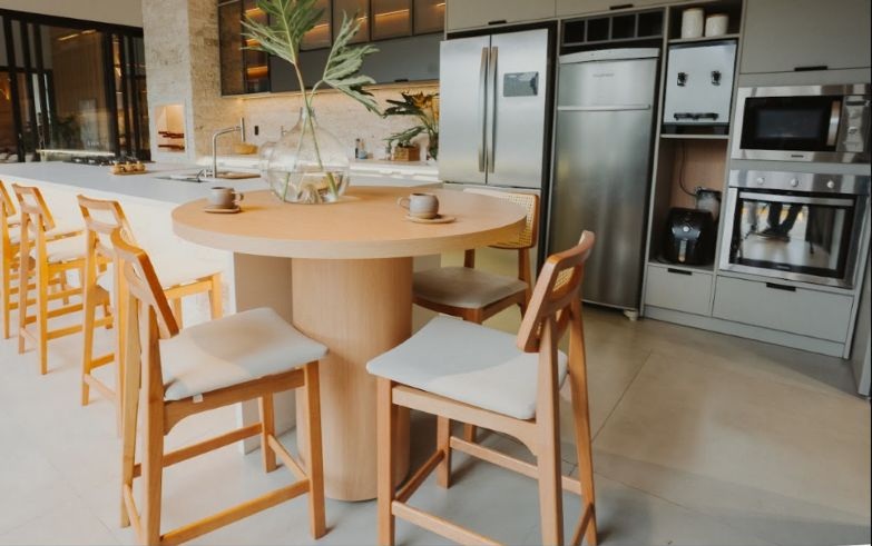 Cozinha integrada da Casa Aldeia com ilha central, armários claros e marcenaria amadeirada