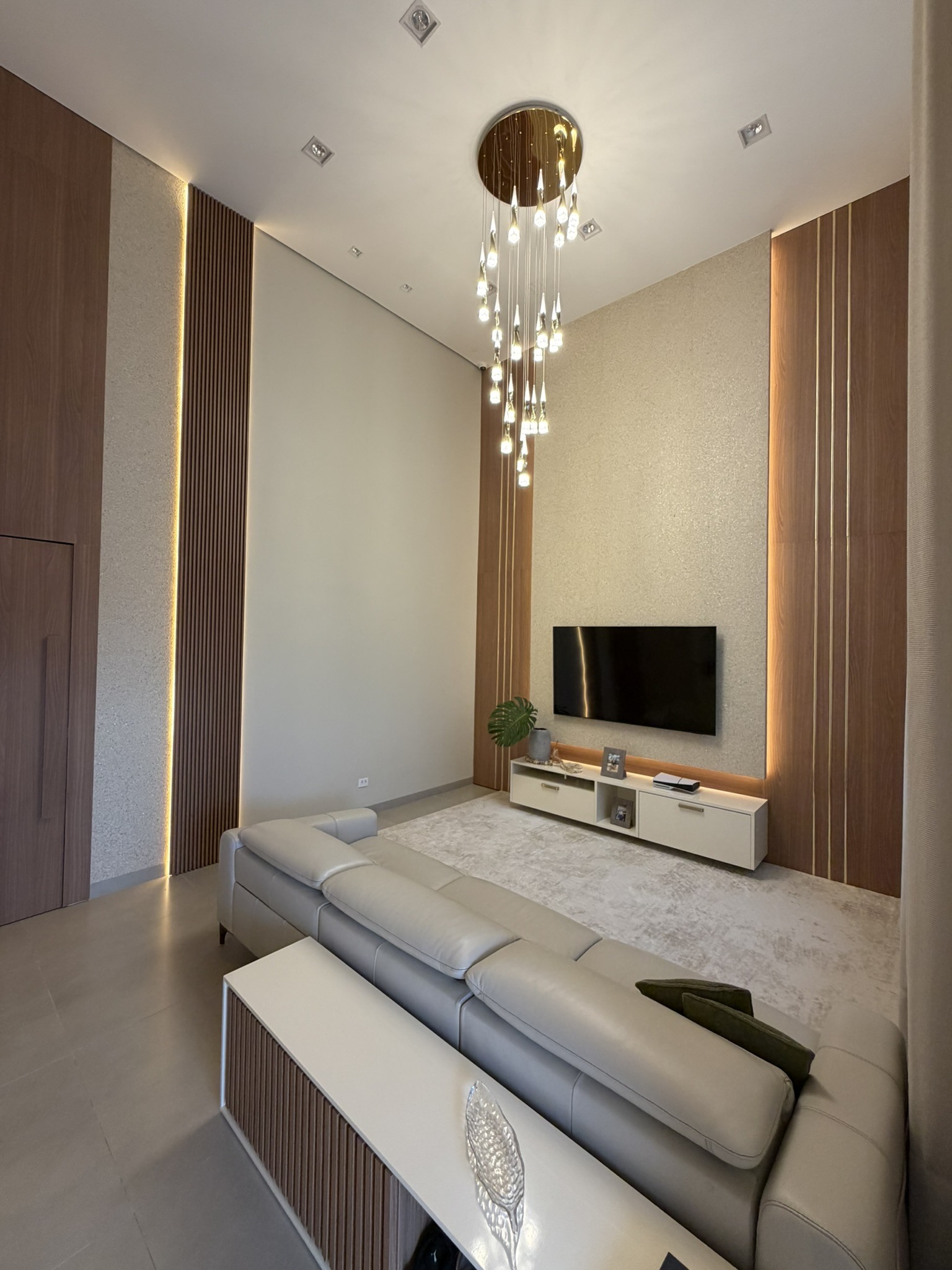 Sala com painel de TV em pé-direito alto